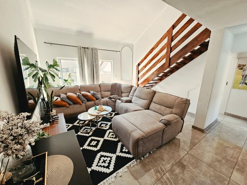 A comfortable living room featuring tiled flooring, a wooden staircase, and coved ceilings, creating a warm and inviting atmosphere.