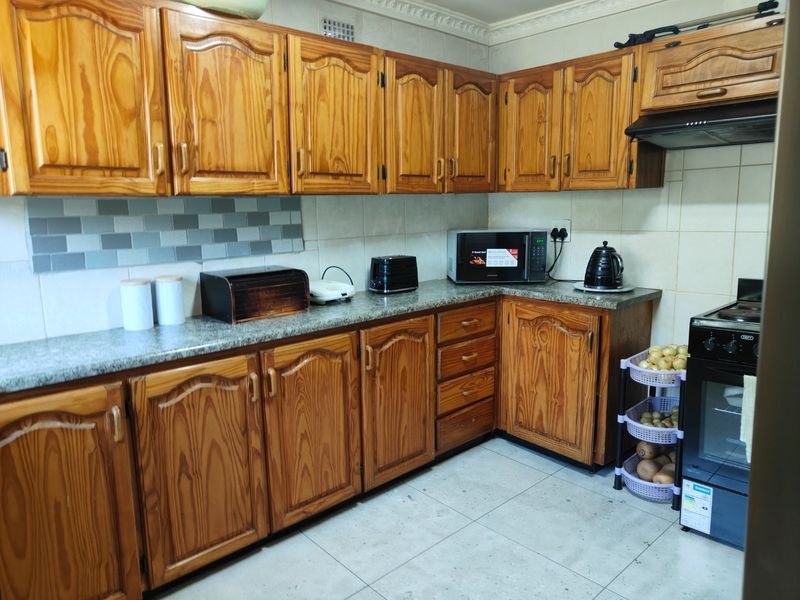 A functional kitchen featuring traditional wooden cabinetry, granite countertops, a tiled backsplash, and a freestanding oven with an integrated extractor fan.