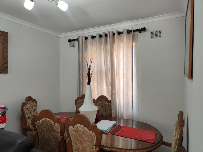 A dining room featuring neutral walls, coving, and a window with curtain rod, providing a functional space for meals.