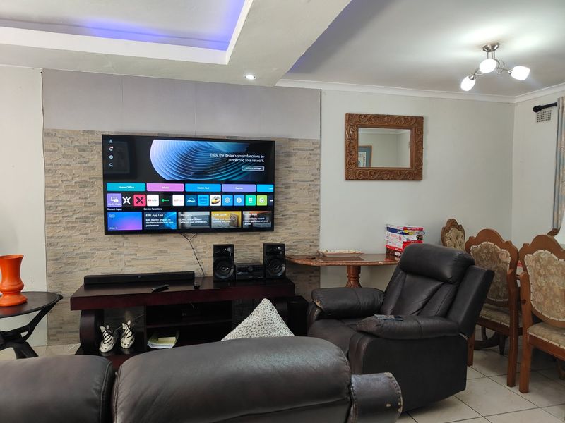 A living room featuring a stone accent wall, recessed ceiling lighting, and tiled flooring, providing a functional space for entertainment.