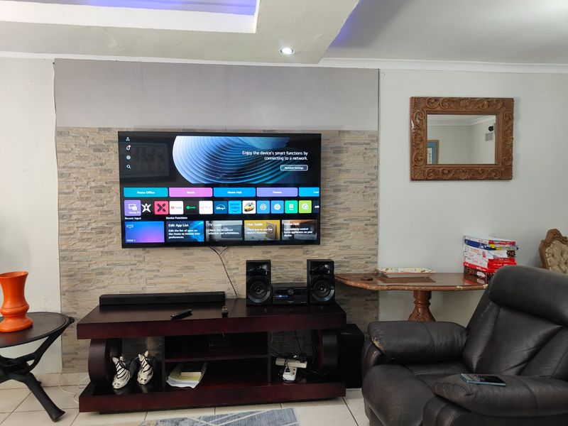 Living room featuring a stone-clad accent wall with integrated television and recessed ceiling lighting.