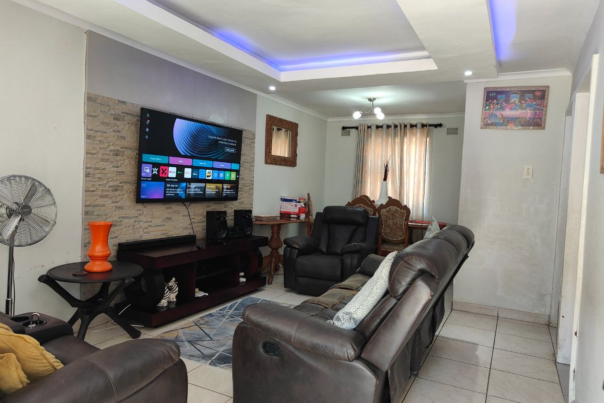 A living room featuring a stone veneer accent wall, recessed ceiling with integrated LED lighting, and neutral ceramic floor tiles.