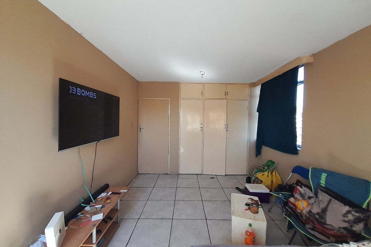 A bedroom featuring tiled flooring and built-in cupboards, offering functional storage space with potential for cosmetic updates to enhance the room's aesthetic.