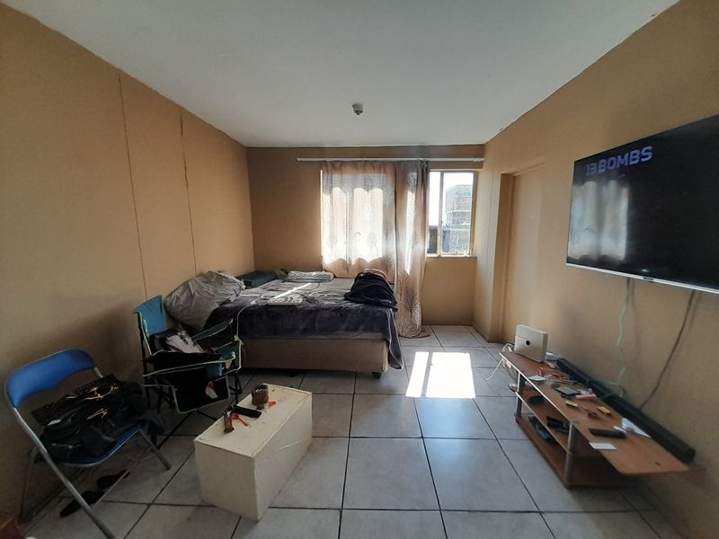 A bedroom featuring tiled flooring and a window with curtain rod, requiring cosmetic updates to the wall finishes.