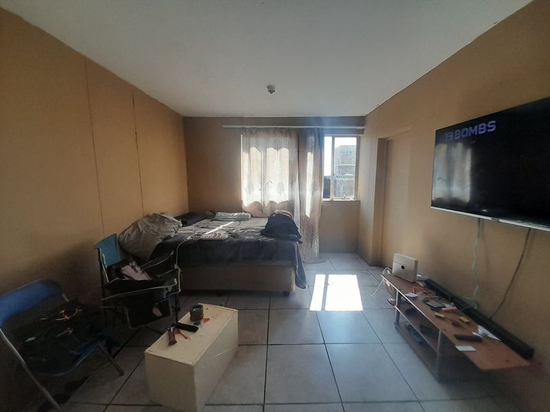 A bedroom featuring tiled flooring and a window, currently used as a multi-purpose living space.