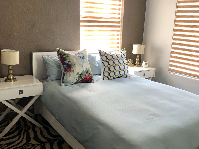 A well-maintained bedroom featuring an accent wall and modern zebra blinds, providing a comfortable and functional living space.