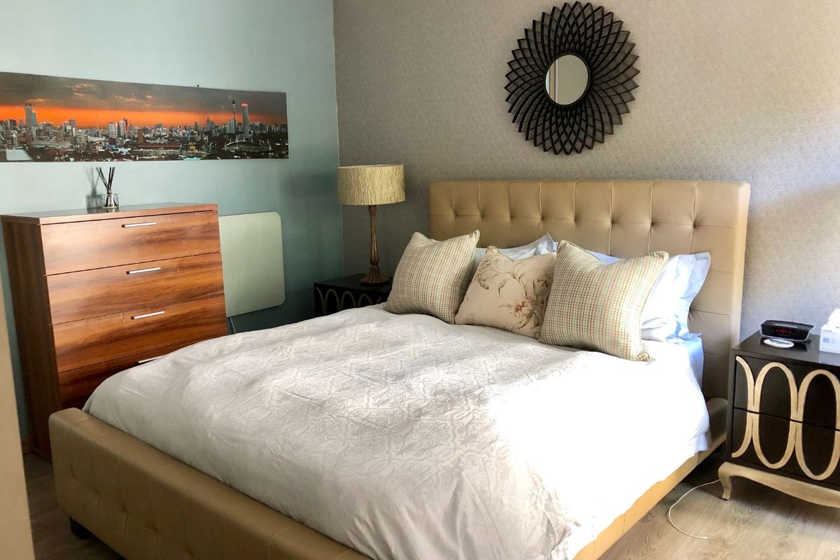 A well-maintained bedroom featuring laminate flooring and neutral wall finishes, providing a comfortable and functional living space.