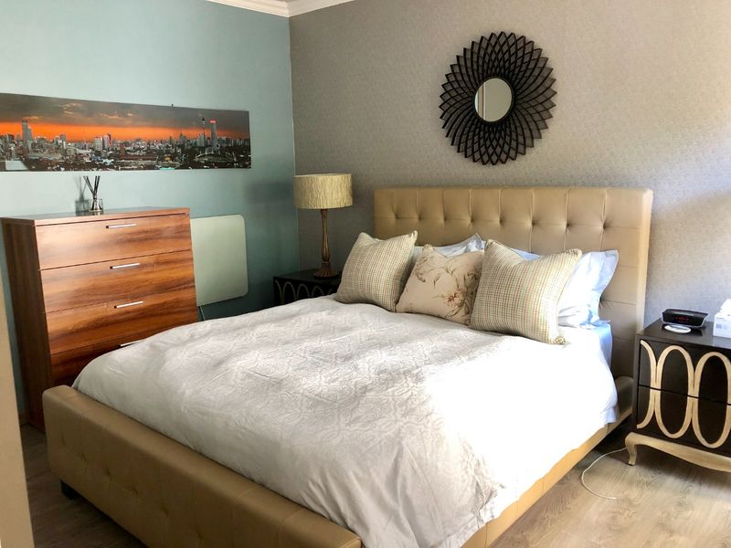 A well-maintained bedroom featuring laminate flooring and neutral wall finishes, providing a comfortable and functional living space.