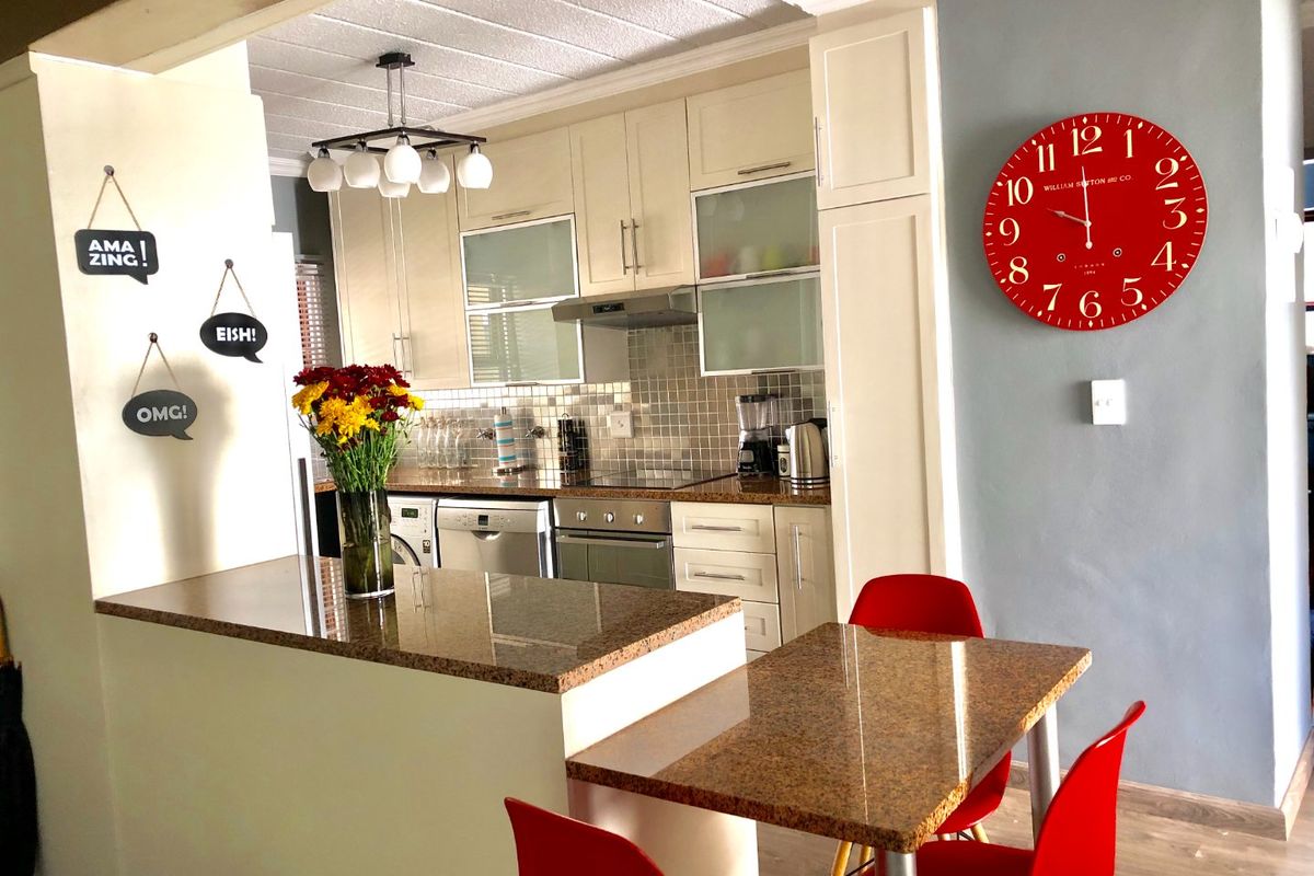A functional kitchen featuring granite countertops, built-in cabinetry, a tiled backsplash, and an integrated breakfast nook area.