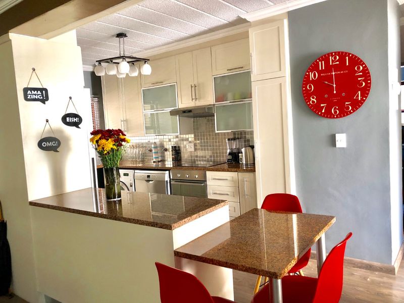 A functional kitchen featuring granite countertops, built-in cabinetry, a tiled backsplash, and an integrated breakfast nook area.