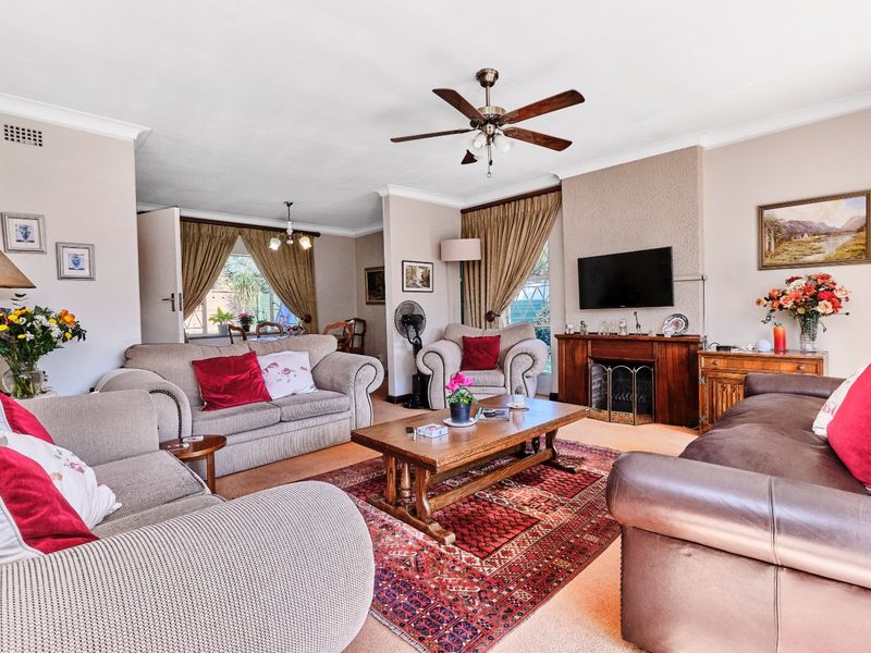 Spacious open-plan living area featuring a central fireplace, ceiling fan, and neutral wall finishes, providing a comfortable and versatile family space.