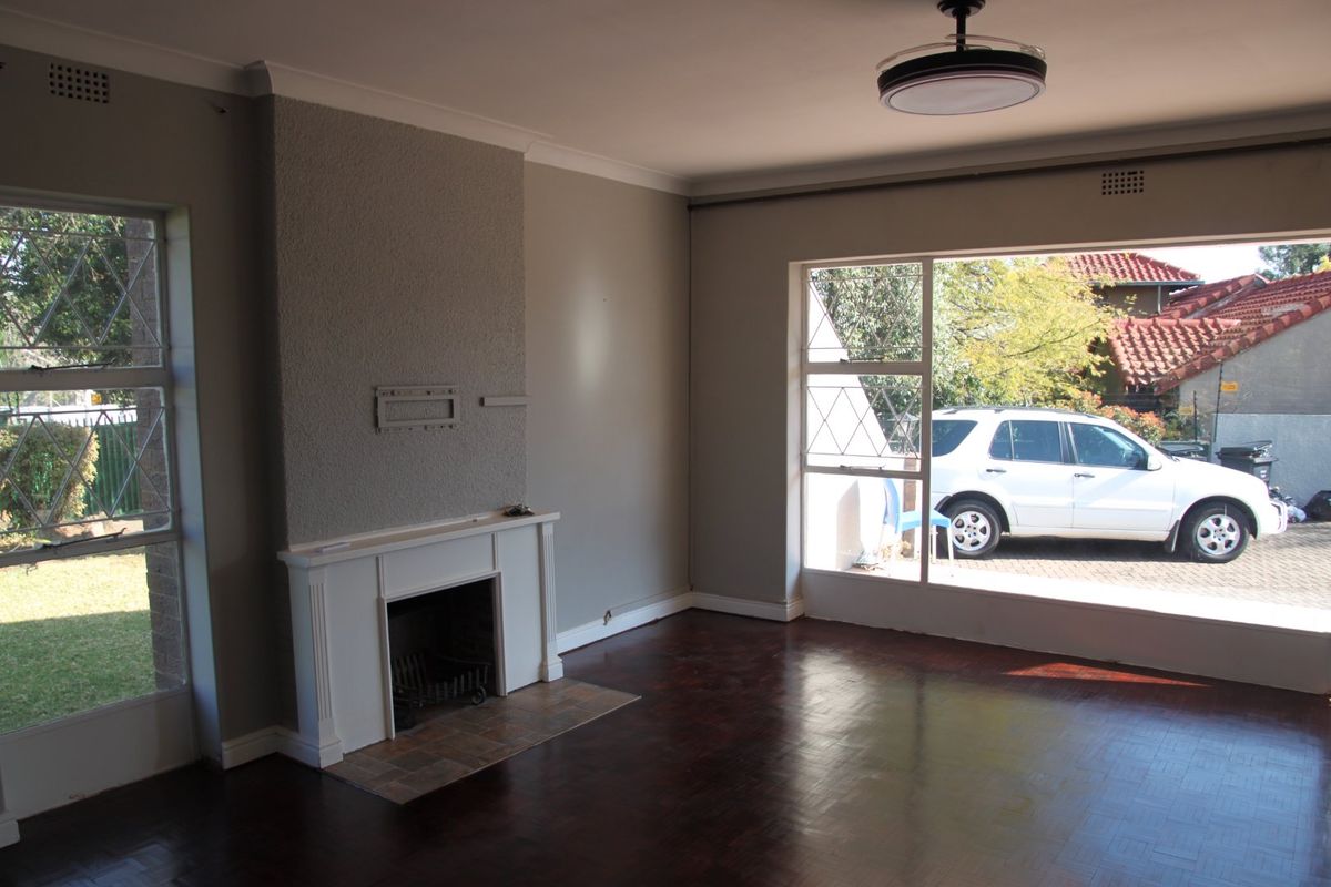 Spacious living room featuring a fireplace, parquet flooring, and large windows providing ample natural light.