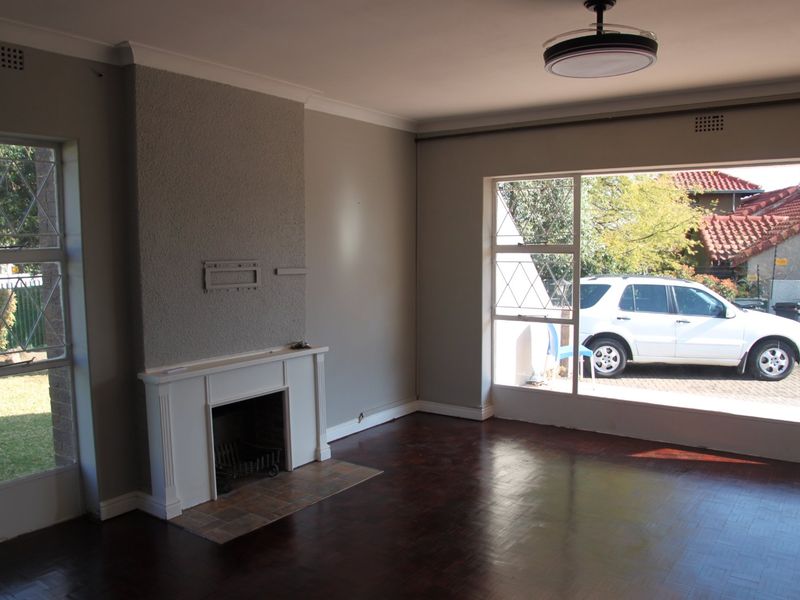 Spacious living room featuring a fireplace, parquet flooring, and large windows providing ample natural light.