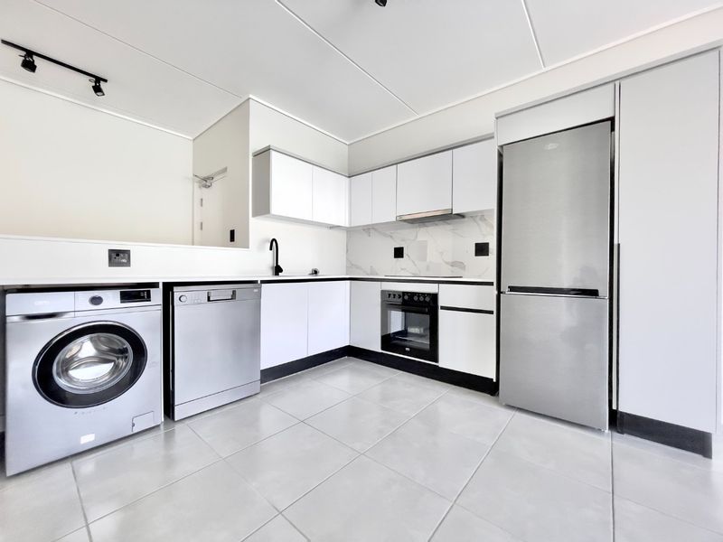 Modern kitchen featuring sleek white cabinetry, marble-look splashback, integrated appliances, and contemporary black fixtures with neutral floor tiling.