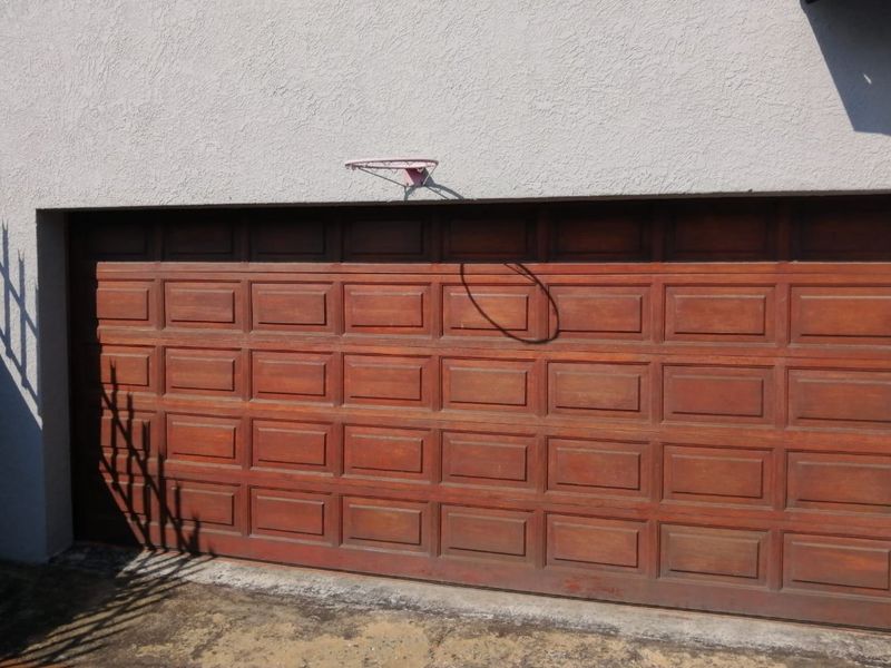 A single garage featuring a traditional wooden sectional door and a concrete driveway.