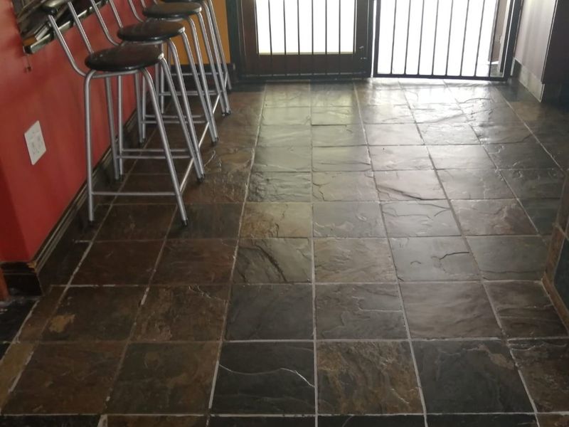 A kitchen area featuring natural slate floor tiles and a secure metal gate leading to the exterior.