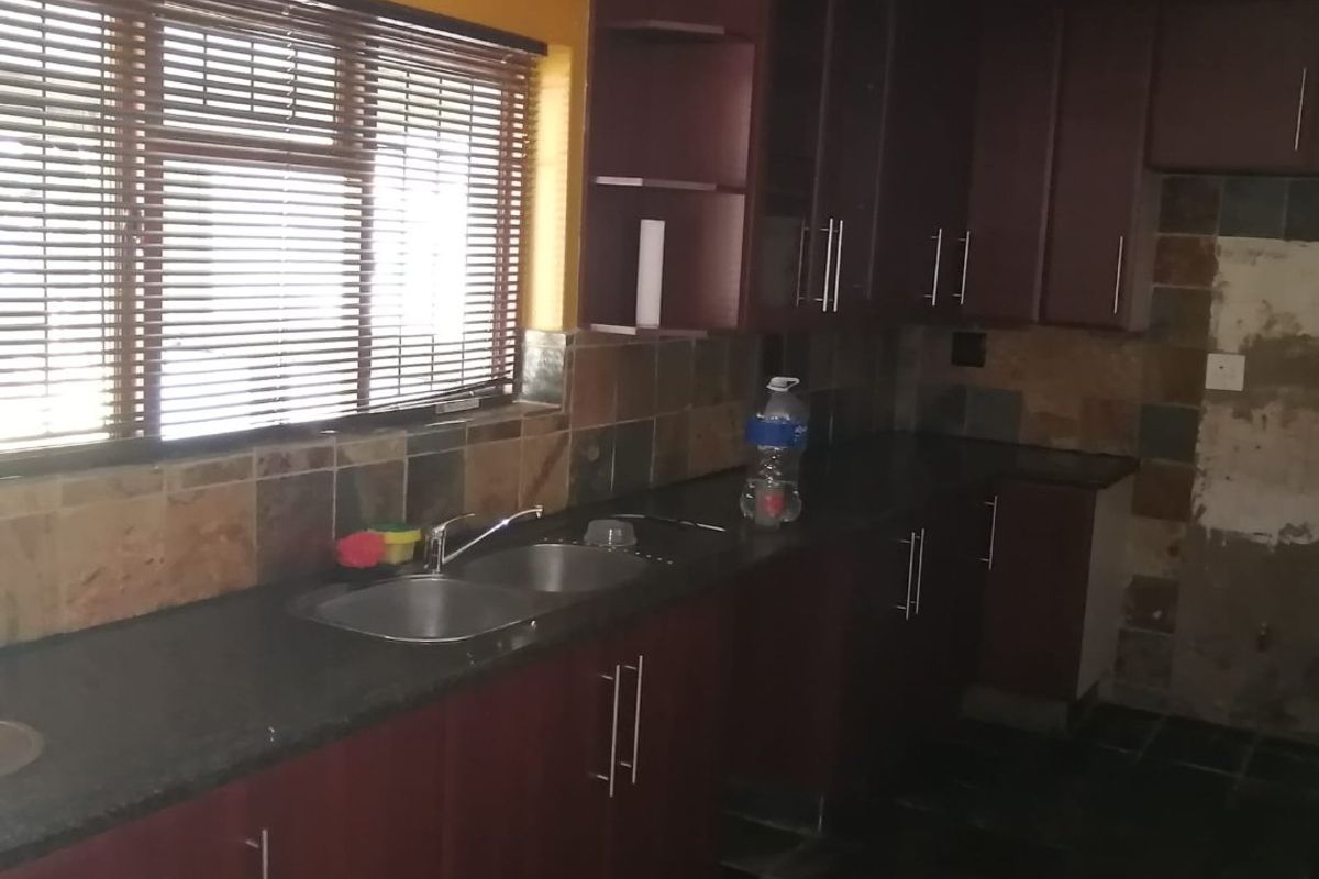 Kitchen featuring dark cabinetry, stone countertops, and slate tile finishes. The space requires cosmetic updates to the wall and backsplash area.