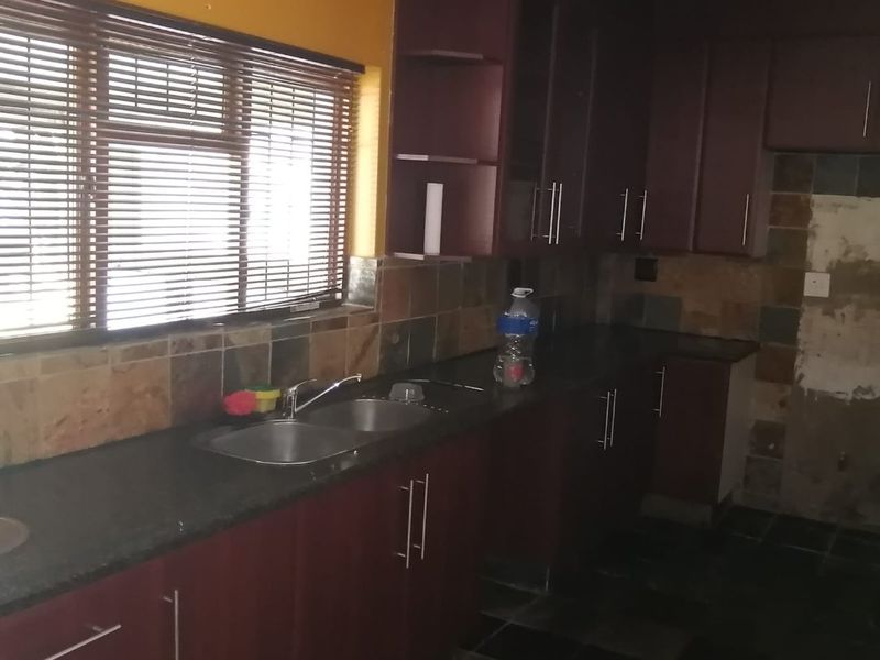 Kitchen featuring dark cabinetry, stone countertops, and slate tile finishes. The space requires cosmetic updates to the wall and backsplash area.