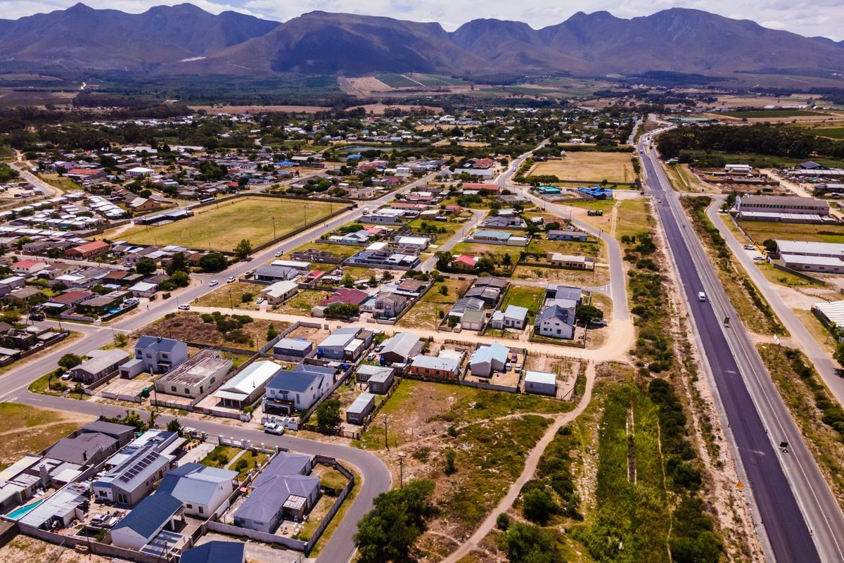 An aerial view of a residential neighborhood featuring established housing, paved road infrastructure, and a scenic mountain backdrop.