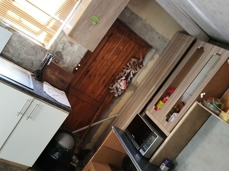 A kitchen space featuring built-in cabinetry, a gas hob, and oven, currently requiring significant wall finishing and renovation to complete the interior.