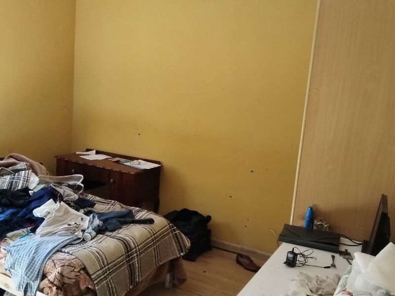 A bedroom featuring laminate flooring and a built-in wardrobe, requiring cosmetic updates to the wall finishes.