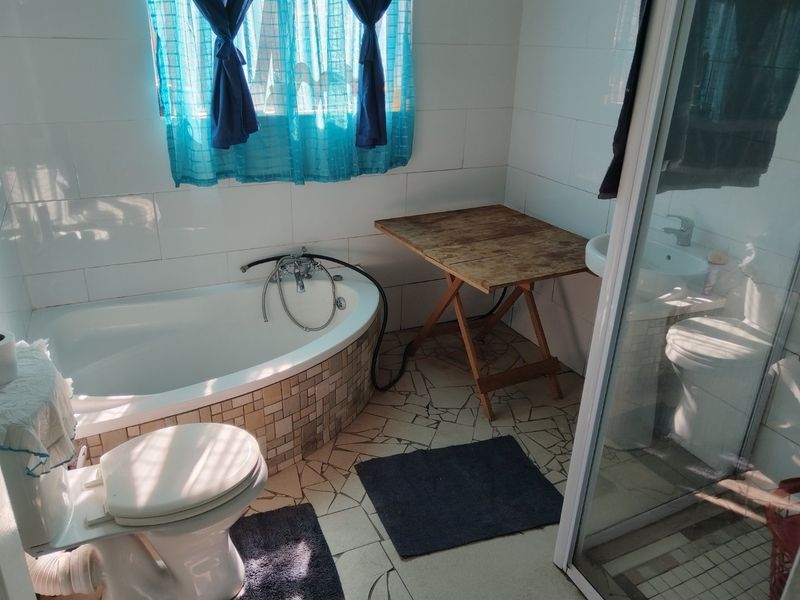 A bathroom featuring a built-in bathtub with mosaic tiling, a separate glass shower enclosure, a pedestal basin, and a toilet with tiled finishes.