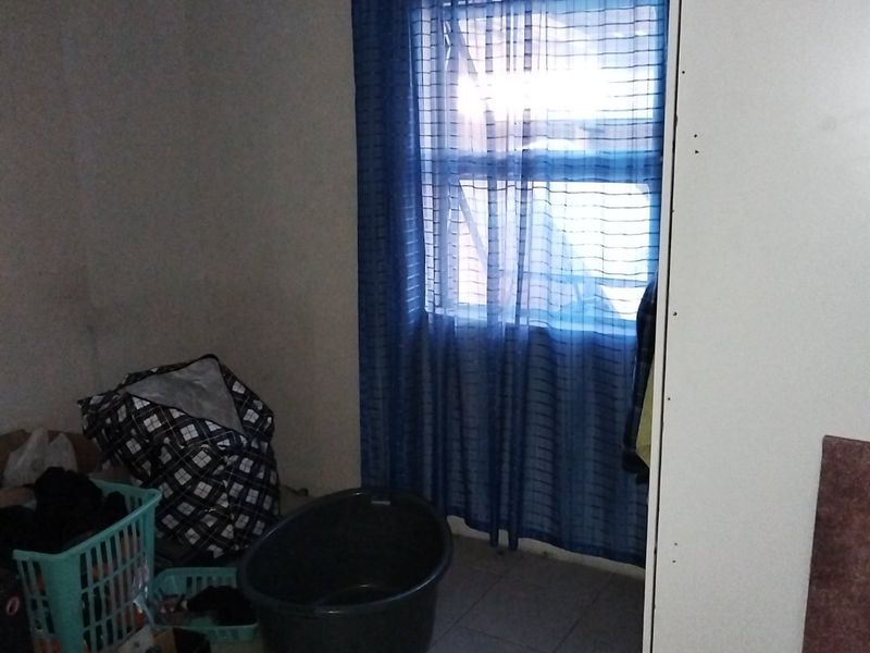 A bedroom featuring tiled flooring and a built-in cupboard, currently requiring maintenance and improved lighting to enhance the space.