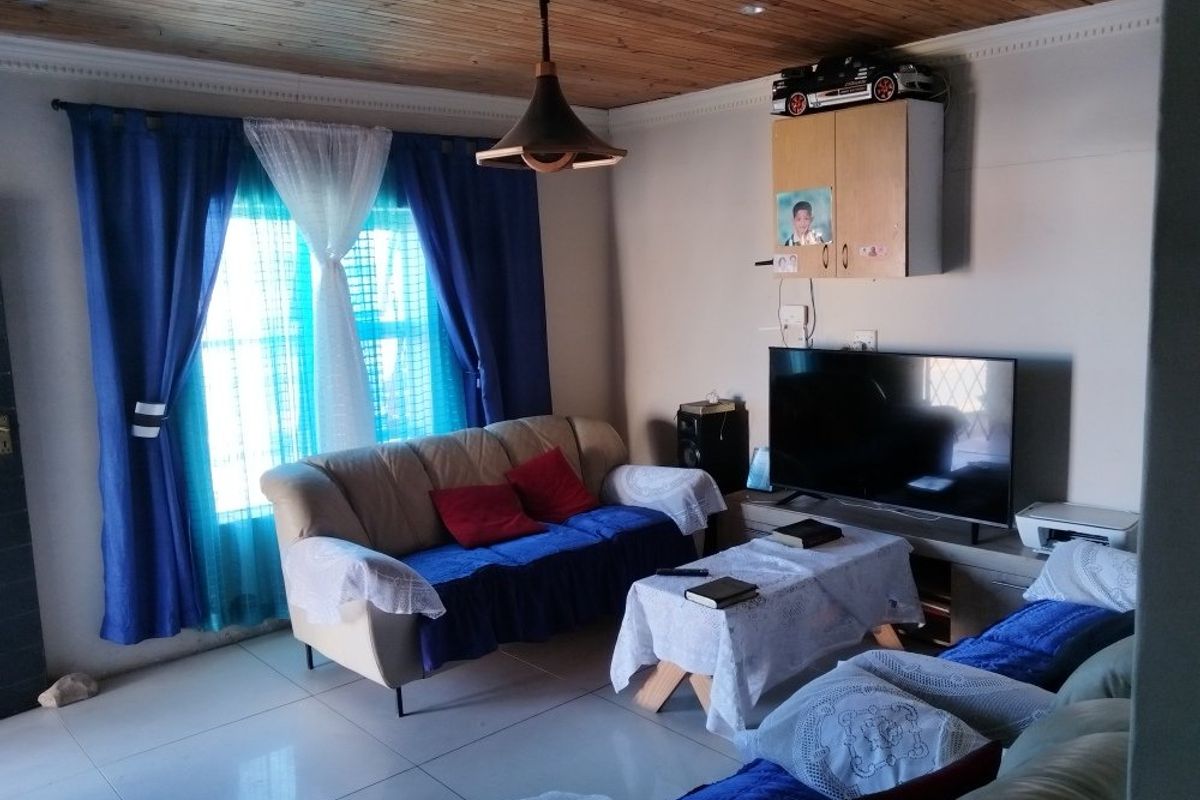 A living room featuring a timber-clad ceiling, tiled flooring, and a built-in wall cabinet, providing a functional and cozy living space.