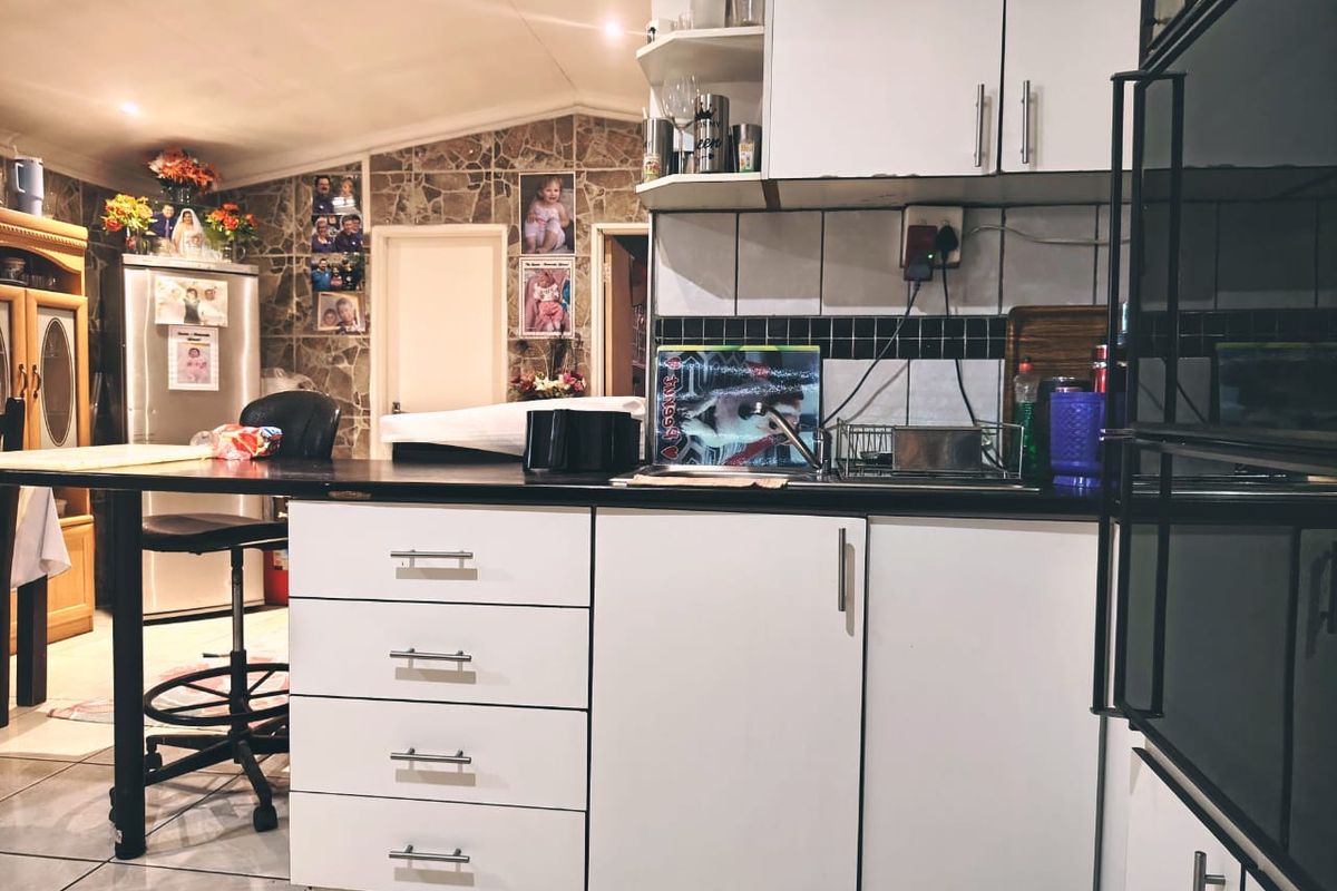 A functional kitchen featuring white cabinetry, dark countertops, a built-in oven, and tiled backsplash, offering a practical layout for daily meal preparation.