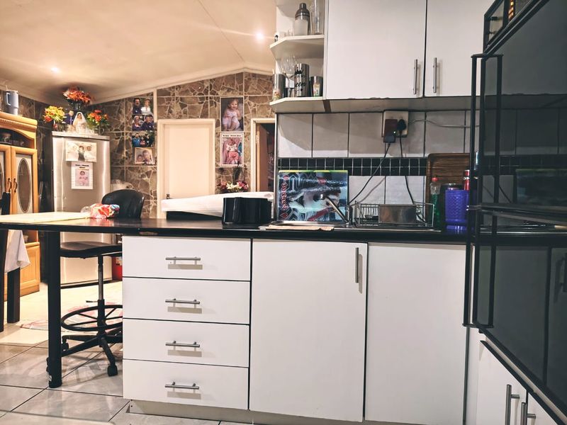 A functional kitchen featuring white cabinetry, dark countertops, a built-in oven, and tiled backsplash, offering a practical layout for daily meal preparation.