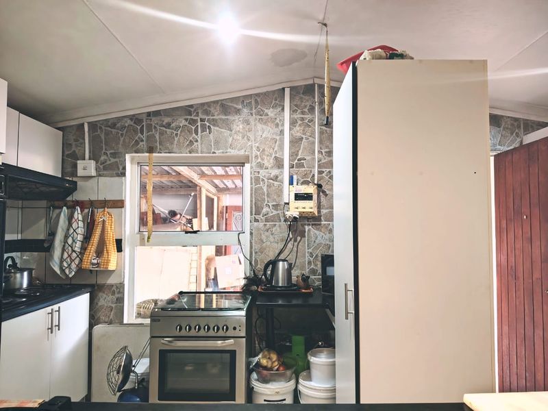 A compact kitchen featuring stone-look wall tiles, built-in cabinetry, and an integrated oven, requiring some maintenance and cosmetic updates.