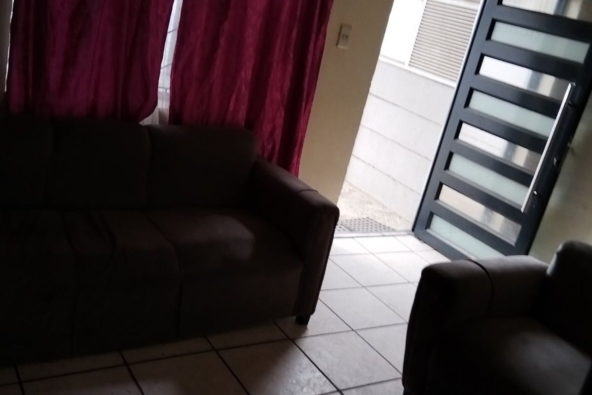 A living room area featuring tiled flooring and a modern panelled front door, providing direct access to the exterior.