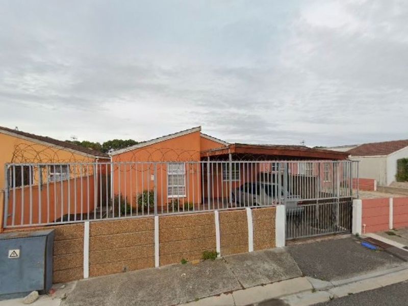 Front elevation of a single-story house featuring a perimeter fence with razor wire, a sliding gate, and a covered carport area.