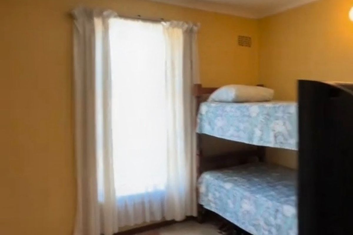 A bedroom featuring yellow walls and a window with curtains, providing a functional space for rest.