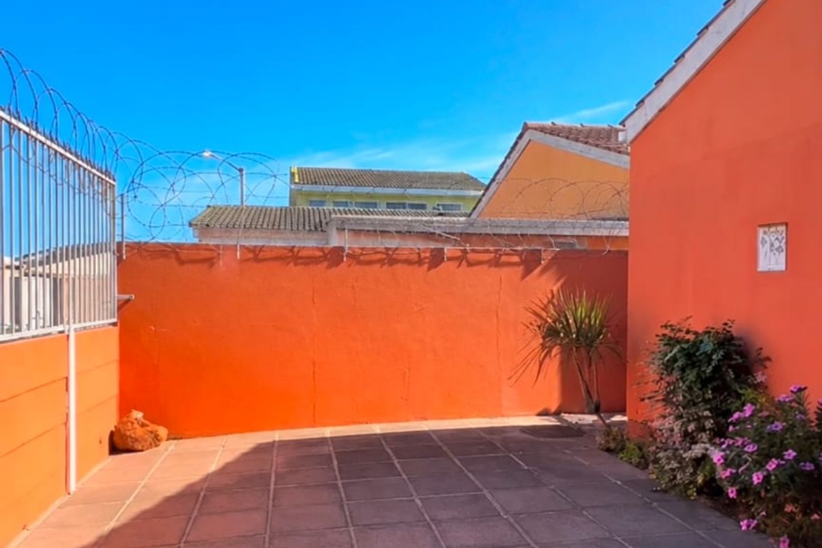 A private rear courtyard featuring paved flooring, high perimeter walls with security razor wire, and a covered patio area.