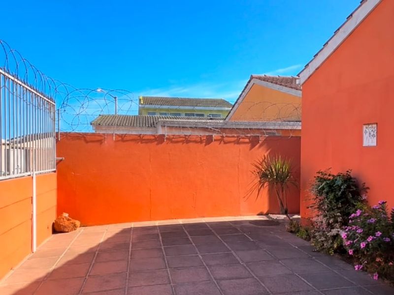 A private rear courtyard featuring paved flooring, high perimeter walls with security razor wire, and a covered patio area.