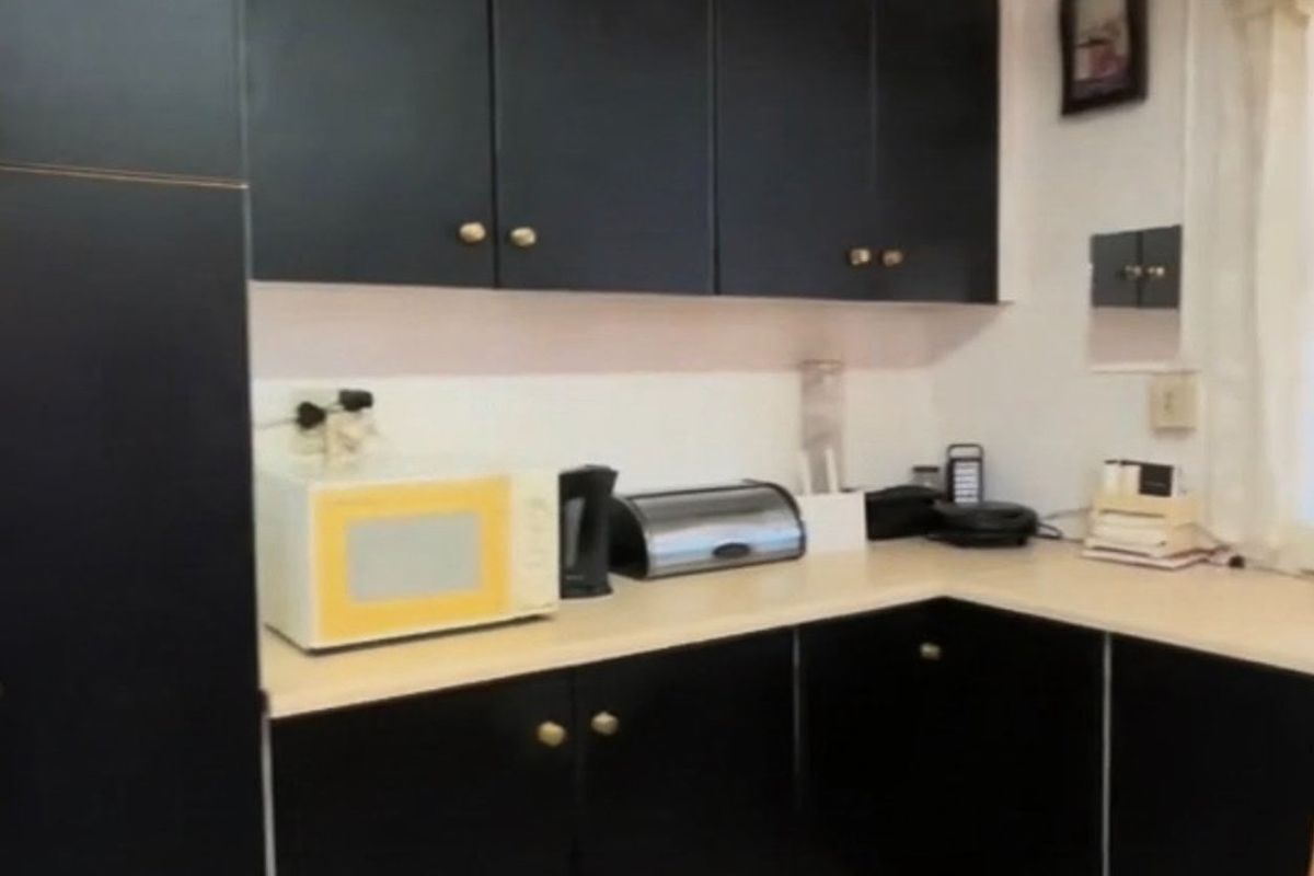 A functional kitchen featuring black cabinetry, light-colored laminate countertops, and tiled flooring.