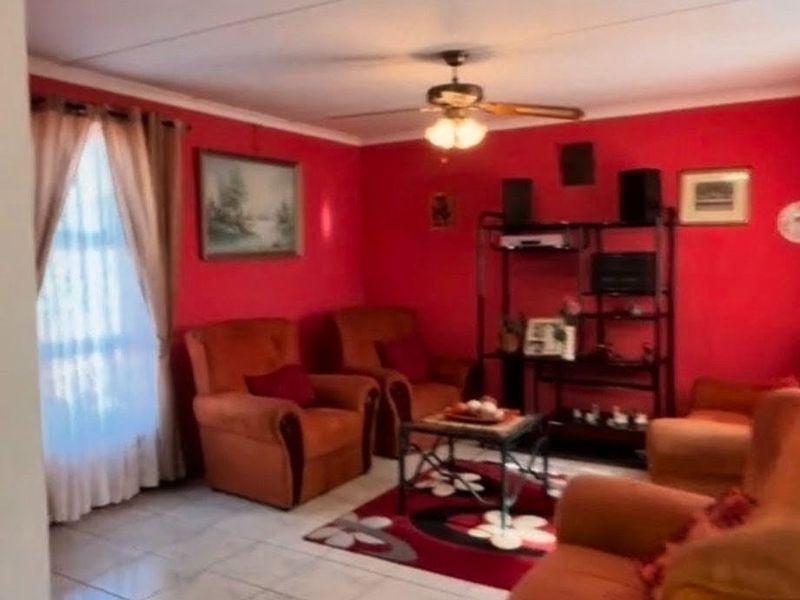 A living room featuring tiled flooring and a ceiling fan, currently finished with bold red wall paint.