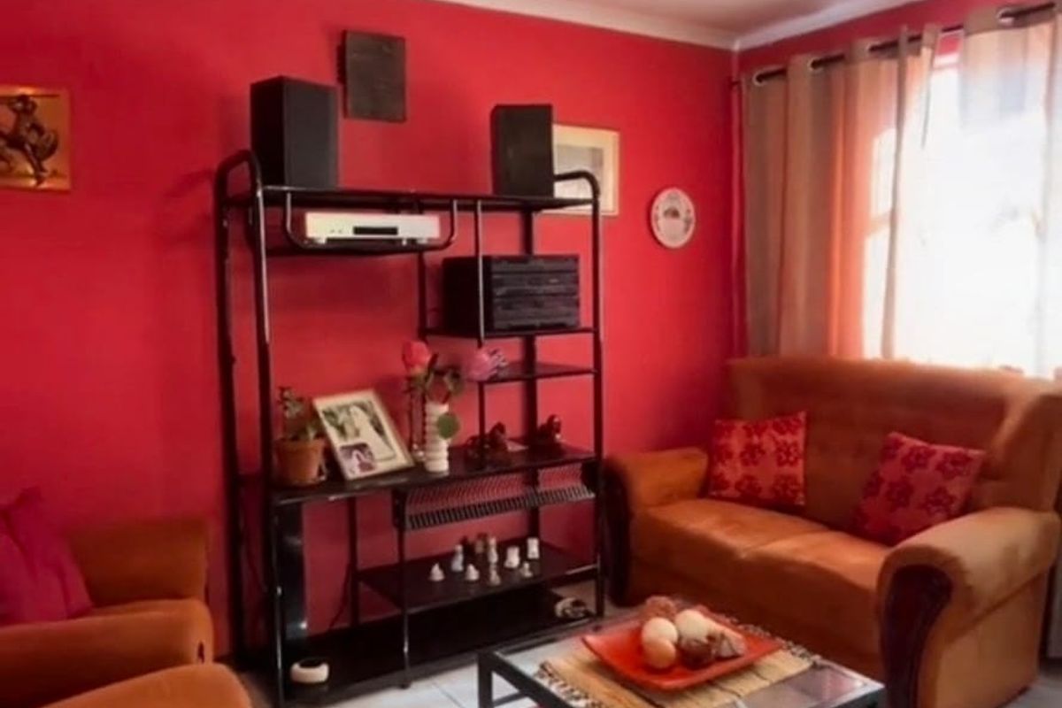 A living room featuring tiled flooring, a ceiling fan, and cove cornicing, currently styled with bold wall colors.