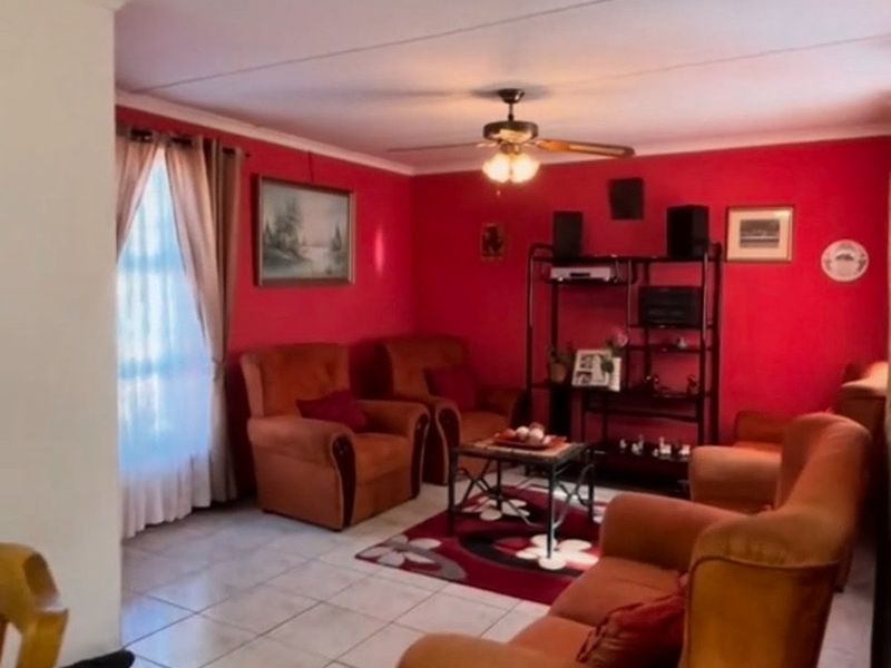 A living room featuring tiled flooring and a ceiling fan, currently styled with a bold red wall finish.