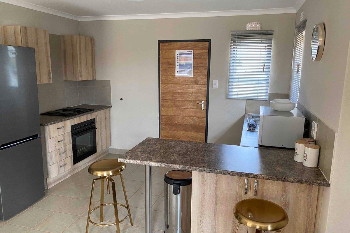 A functional kitchen featuring light wood-look cabinetry, laminate countertops, a built-in oven with gas hob, and tiled flooring.