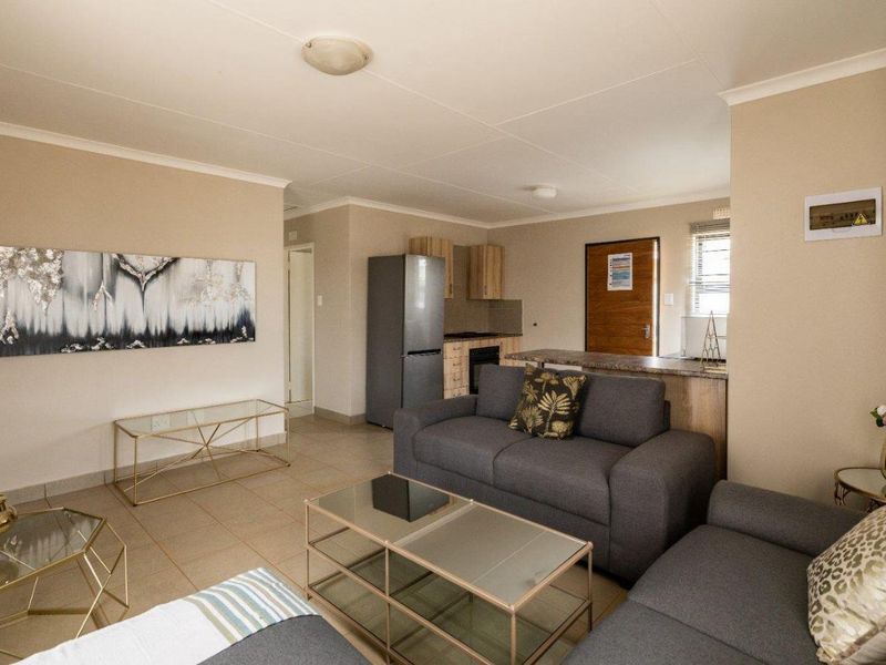An open-plan living area featuring tiled floors, a breakfast bar, and a functional kitchen layout, creating a cohesive and practical living space.