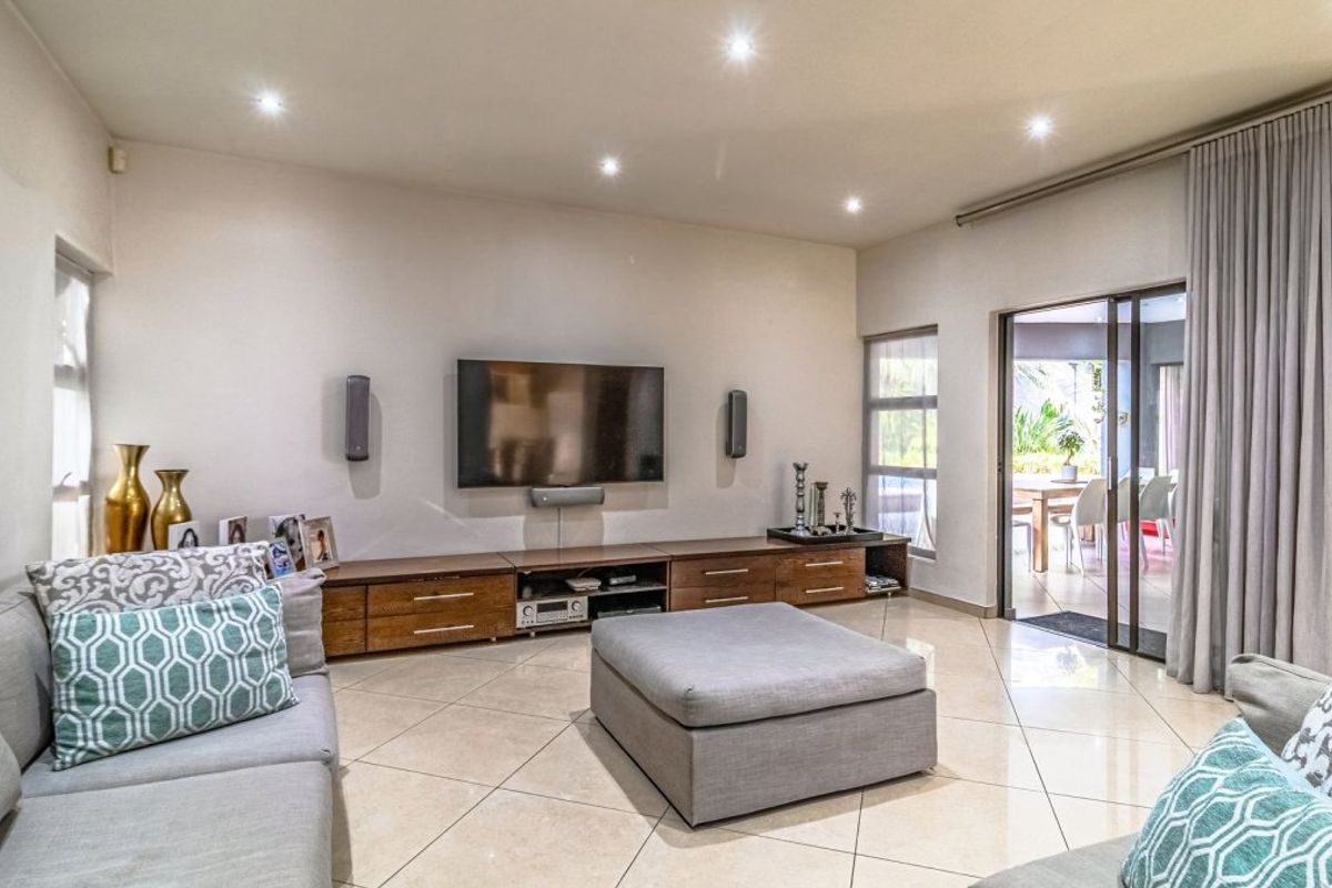 Spacious living room featuring tiled flooring, recessed downlighting, and a large sliding glass door providing seamless access to the outdoor patio area.