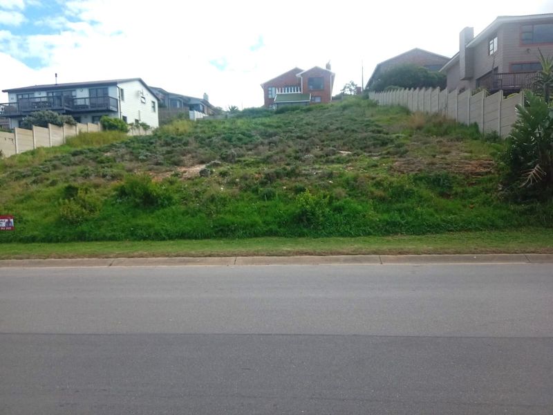 A vacant residential plot featuring a significant upward slope, bordered by existing concrete boundary walls in a developed neighborhood setting.
