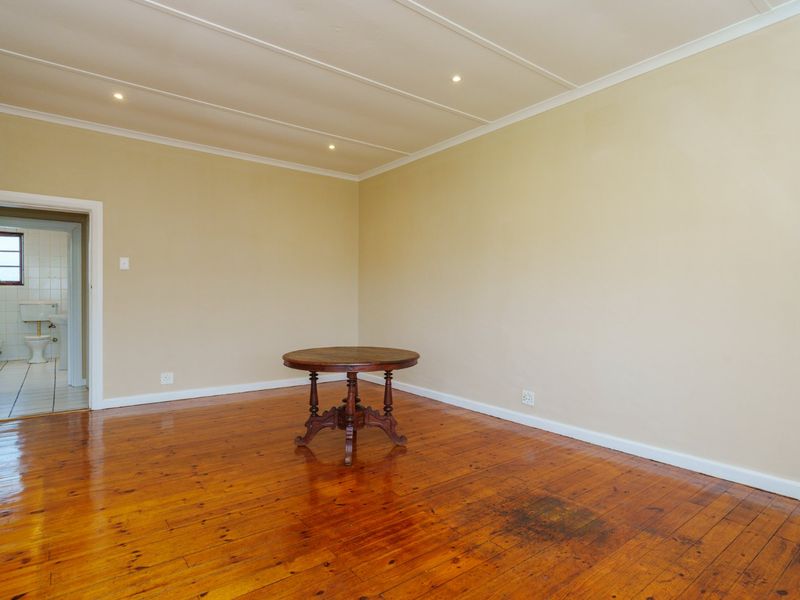 Spacious living area featuring polished hardwood flooring and recessed ceiling lighting, with a view into an adjacent bathroom.