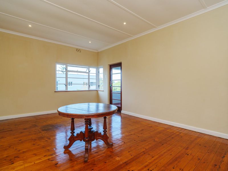 A spacious living area featuring polished timber flooring, recessed downlights, and access to an outdoor area through a timber-framed door.