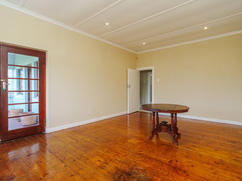 Spacious living area featuring polished hardwood flooring, recessed ceiling lighting, and a timber-framed glass door leading to an outdoor space.