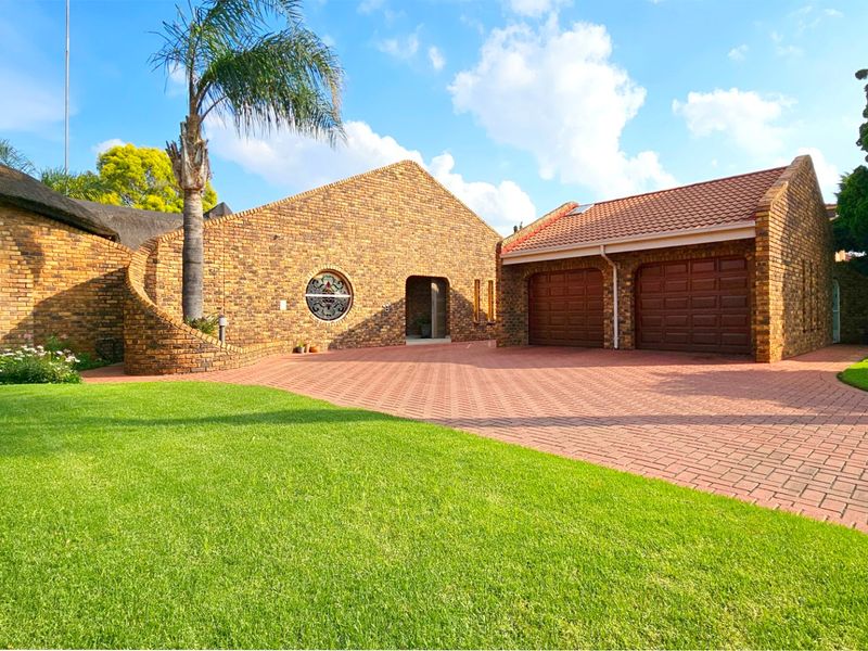Front elevation of a characterful face brick house featuring a double garage, paved driveway, and well-maintained garden.