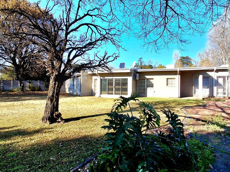 Rear view of the house featuring a spacious garden, brick paved patio area, and secure sliding door access.