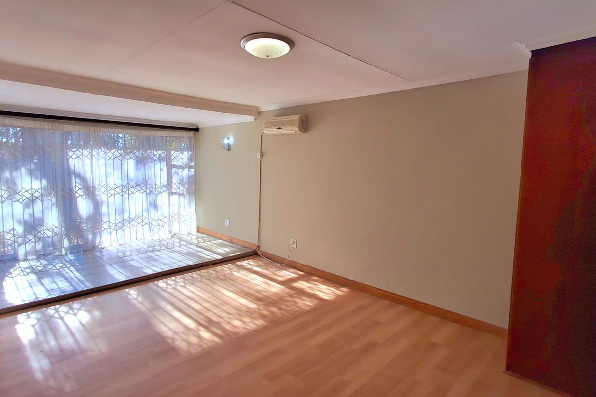 Spacious bedroom featuring laminate flooring, a built-in cupboard, and an air conditioning unit, with large sliding doors leading to an outdoor area.